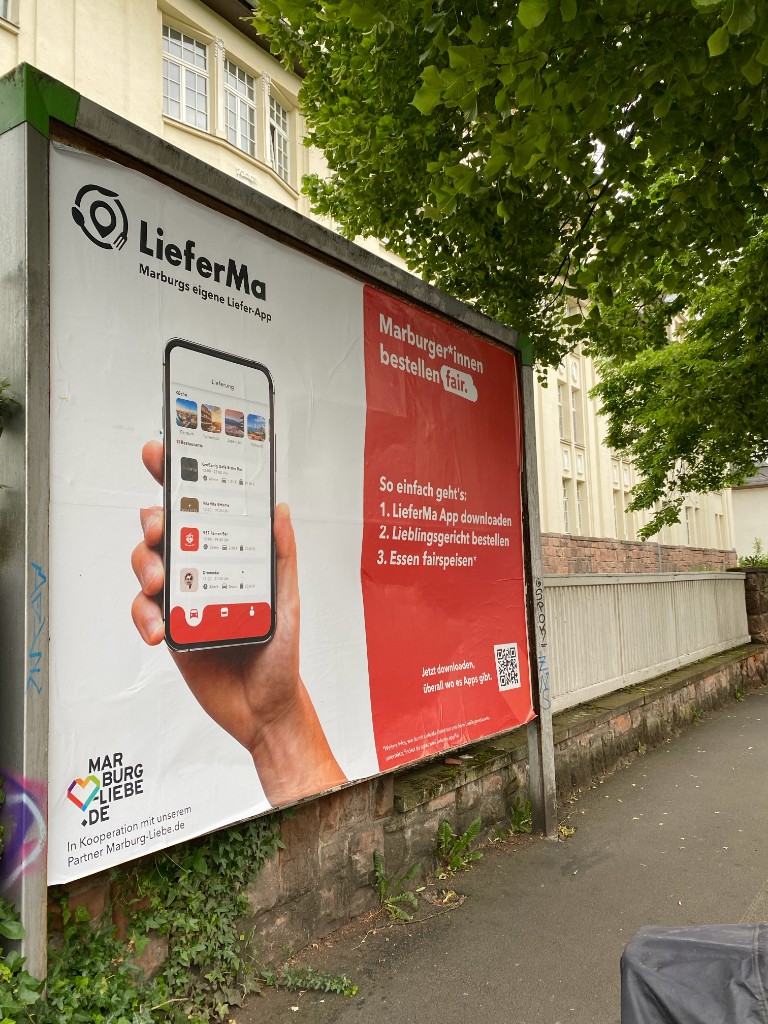 Großflächenplakat für LieferMa, Marburgs Liefer-App, mit Smartphone, QR-Code und dem Satz Marburgerinnen bestellen fair