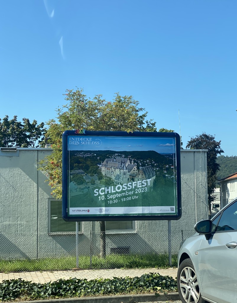Großflächenplakat mit dem grünen Schlossfest-Motiv: Luftaufnahme des Marburger Schlosses und der Termin 10. September 2023